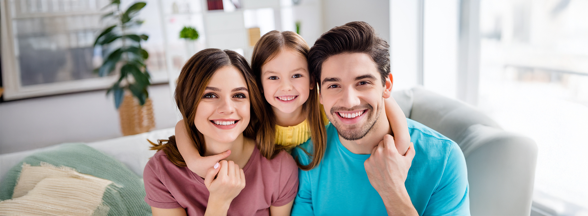 A family of four posing together indoors with a warm smile.