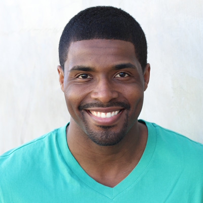 An elderly couple sitting closely together, smiling and posing for the camera.